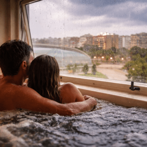 Pareja en jacuzzi privado mirando la lluvia por la ventana de un spa en Valencia