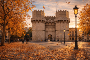 Torres de Serranos de Valencia con ambiente otoñal, árboles dorados y hojas caídas al atardecer.